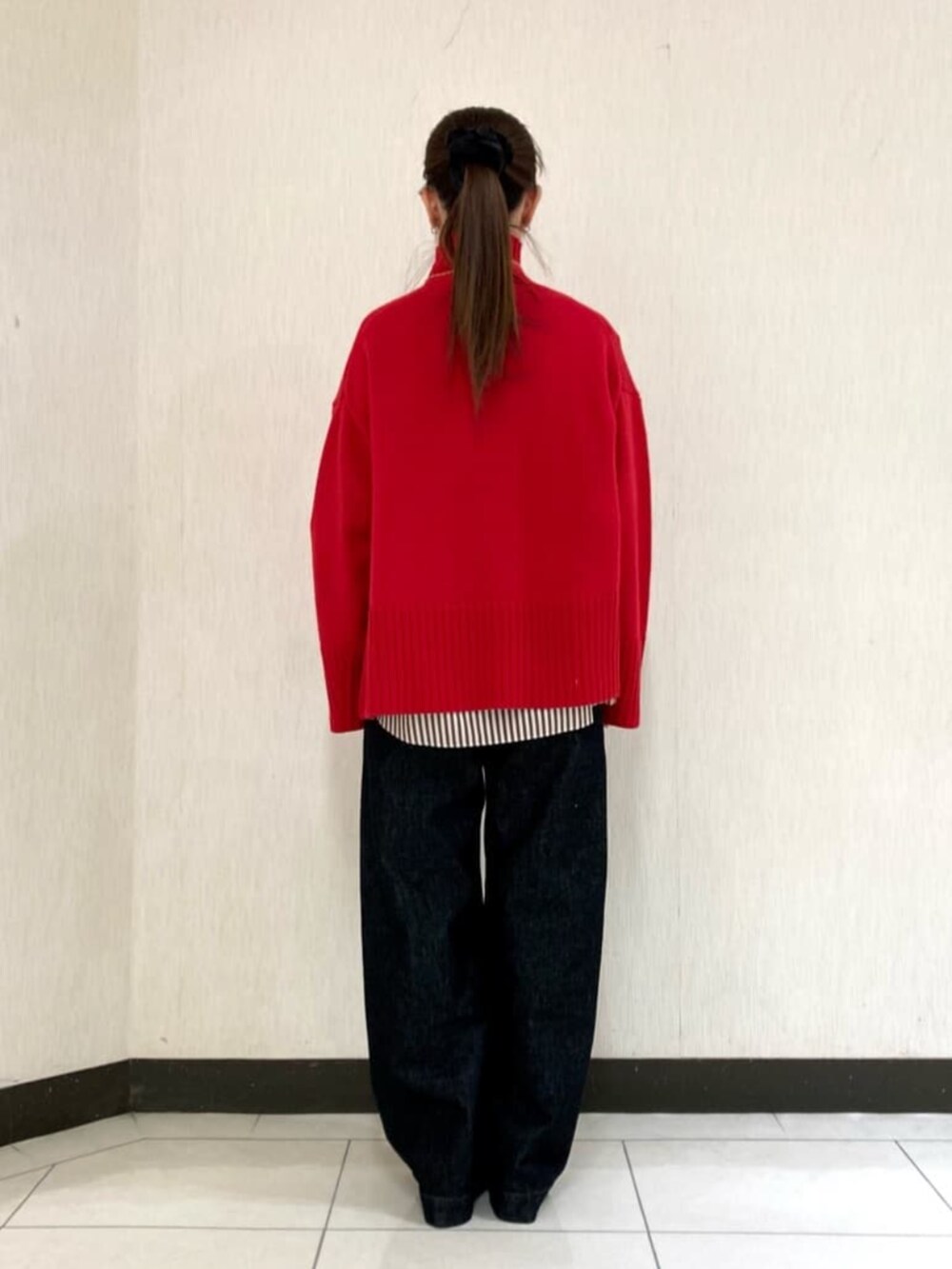 レッド系のニット/セーター、ブラック系のデニムパンツを着用したレディースの冬コーディネートの4枚目の写真