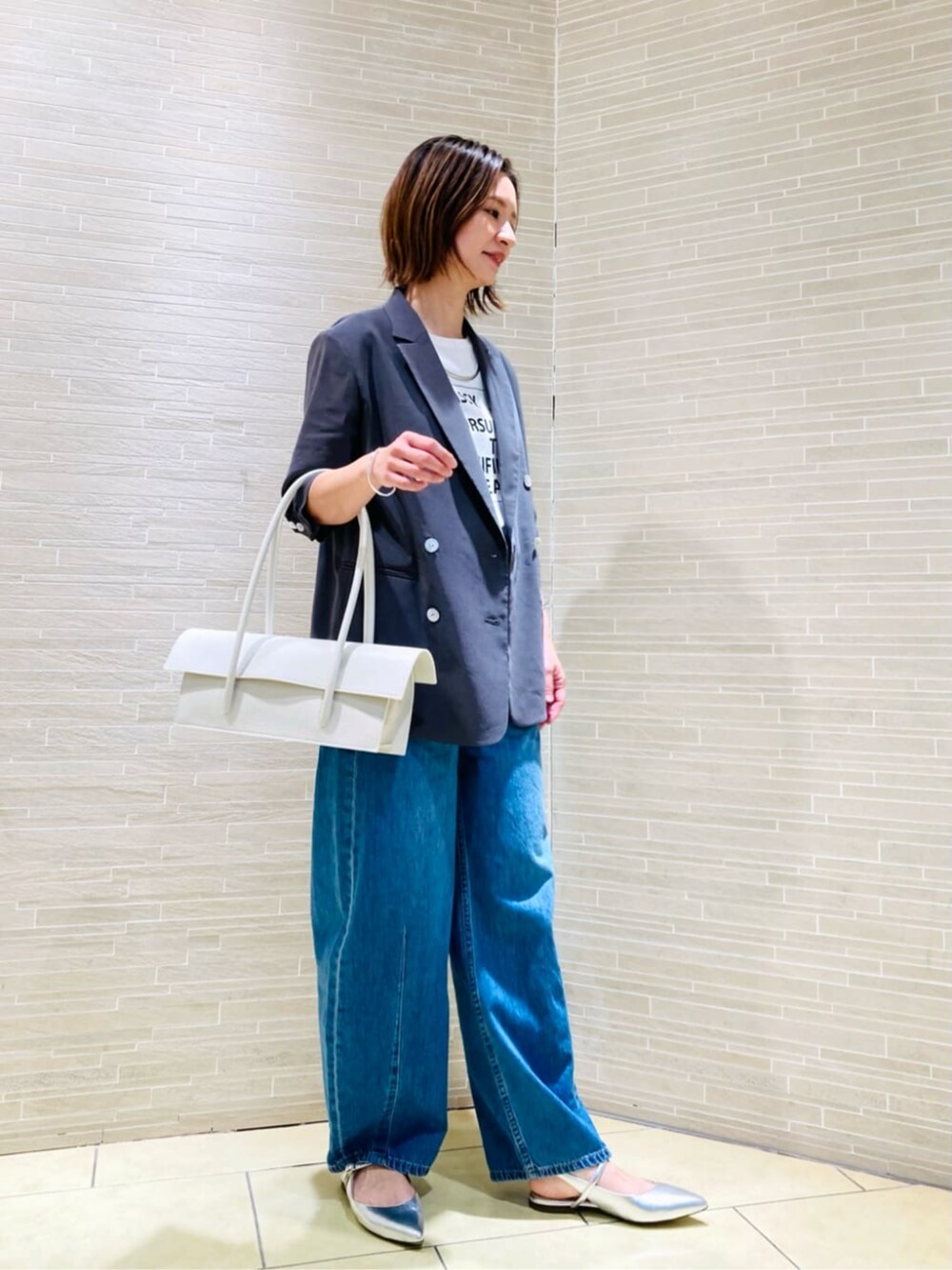 ホワイト系のTシャツ/カットソー、グレー系のテーラードジャケット、ブルー系のデニムパンツを着用したレディースの春コーディネートの3枚目の写真