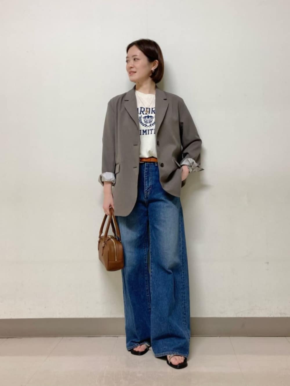 ブラウン系のボストンバッグ、ブルー系のデニムパンツ、ホワイト系のニット/セーターを着用したレディースの春コーディネートの2枚目の写真