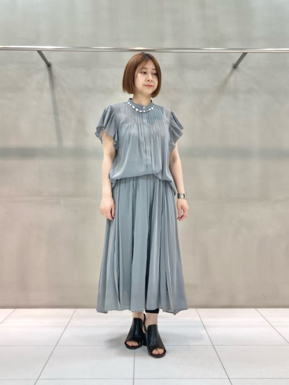 ブラック系のサンダル、グレー系のカーディガン/ボレロ、グリーン系のスカートを着用したレディースの春コーディネートの4枚目の写真