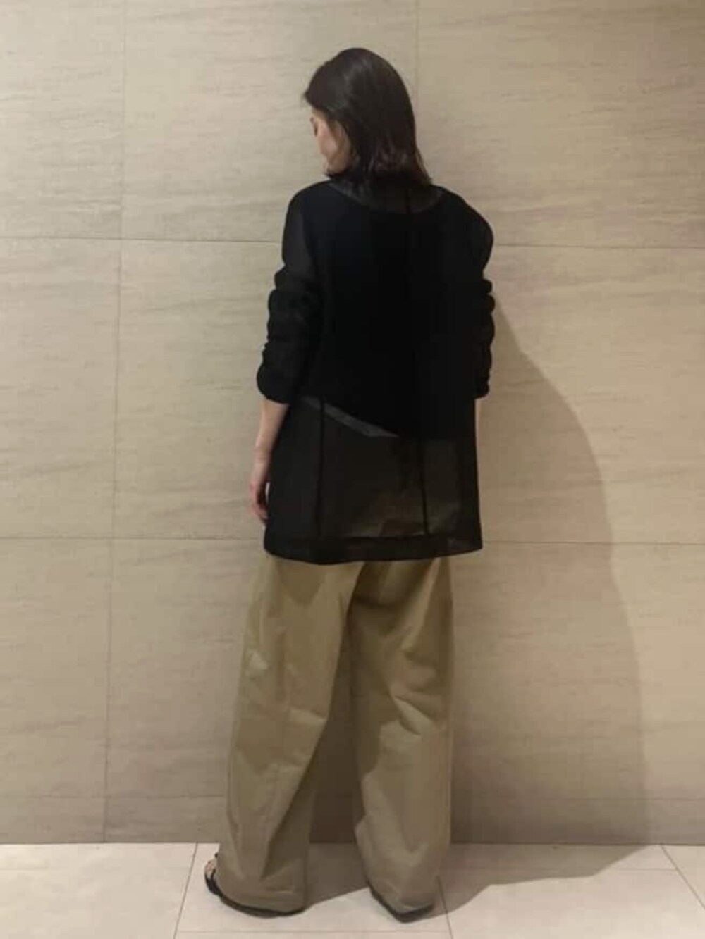 イエロー系のチノパンツ、ブラック系のタンクトップを着用したレディースの夏コーディネートの3枚目の写真