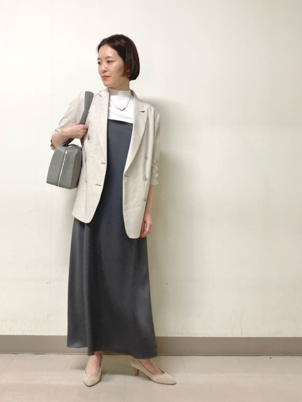 ホワイト系のニット/セーター、グレー系のテーラードジャケット、グレー系のワンピースを着用したレディースの春コーディネートの3枚目の写真