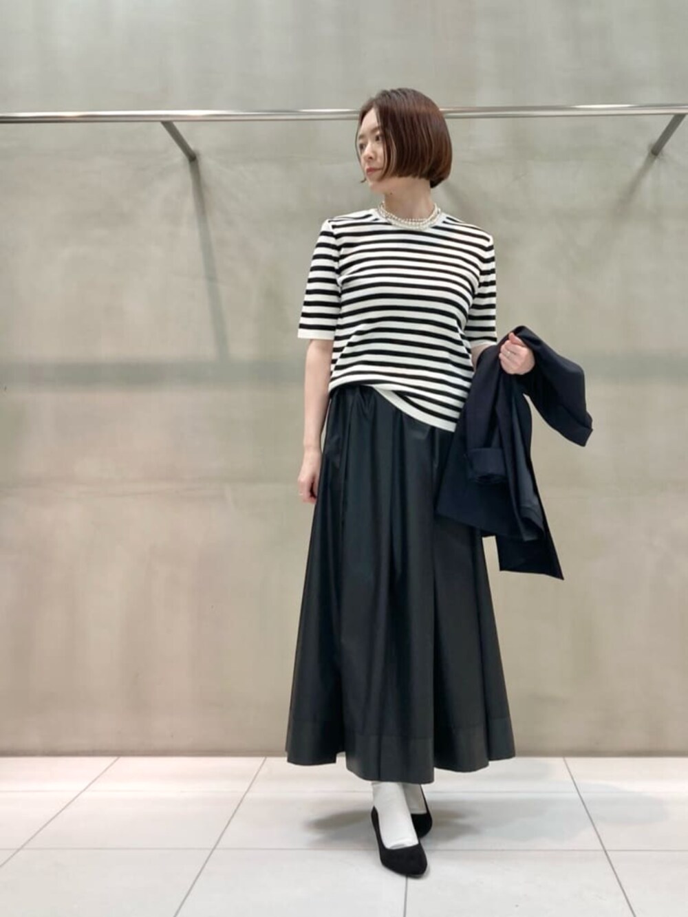 ブルー系のセットアップ、ホワイト系のニット/セーター、ブラック系のスカートを着用したレディースの春コーディネートの2枚目の写真