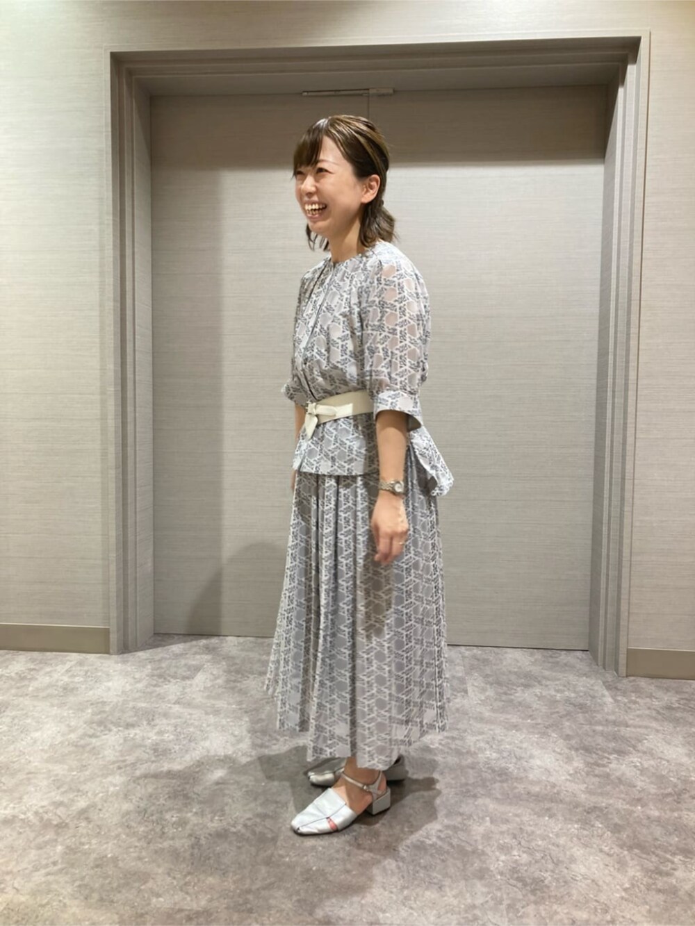 グレー系のシャツ/ブラウス、グレー系のスカート、ホワイト系のベルトを着用したレディースの夏コーディネートの2枚目の写真