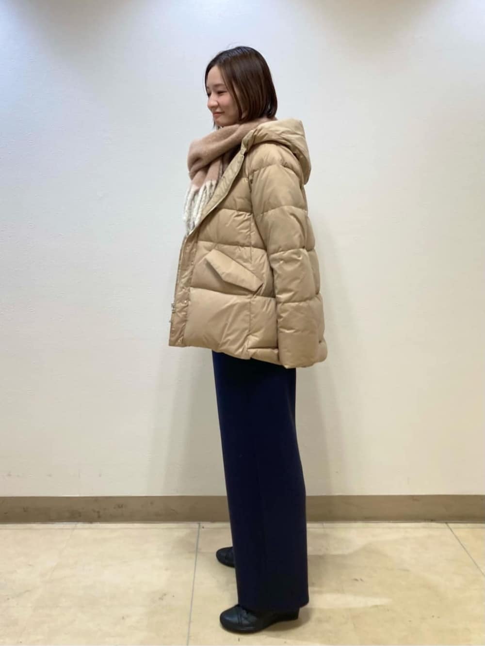 ベージュ系のダウンジャケット/コート、ブルー系のスラックスを着用したレディースの冬コーディネートの4枚目の写真