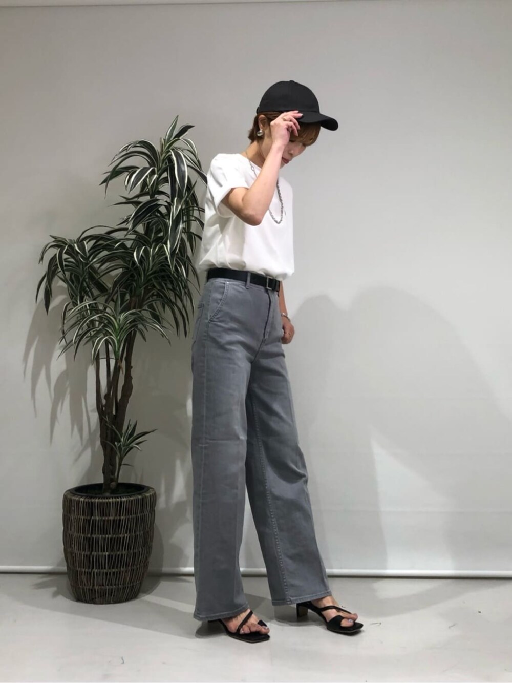 グレー系のデニムパンツ、ホワイト系のトップス、ブラック系のベルトを着用したレディースの夏コーディネートの3枚目の写真