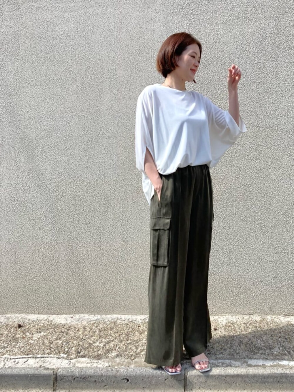 グリーン系のパンツ、ホワイト系のトップスを着用したレディースの夏コーディネートの2枚目の写真