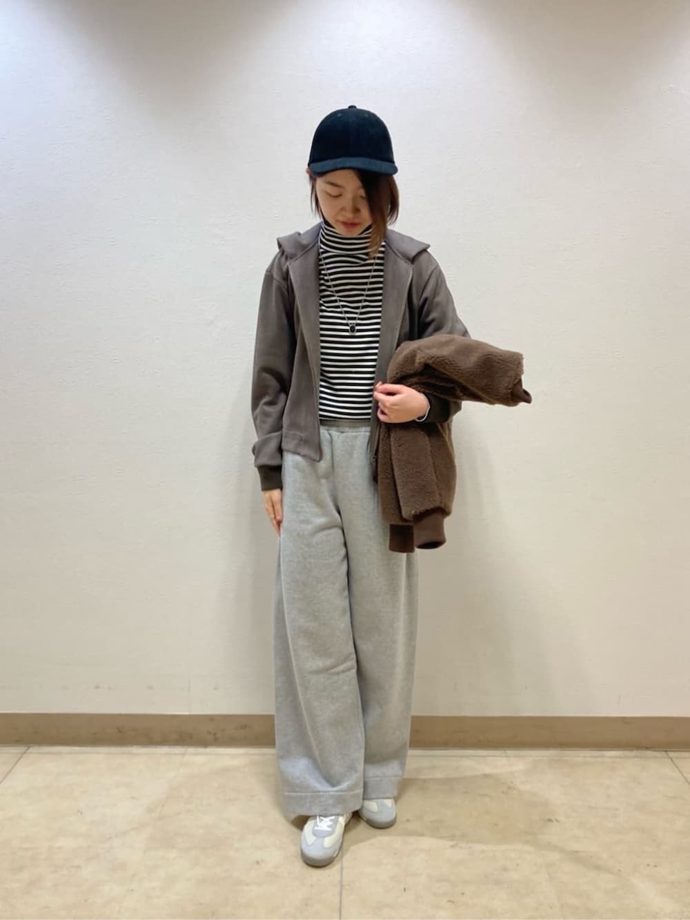 ブラウン系のブルゾン、グレー系のその他パンツ、ブラック系のキャップを着用したレディースの冬コーディネートの4枚目の写真