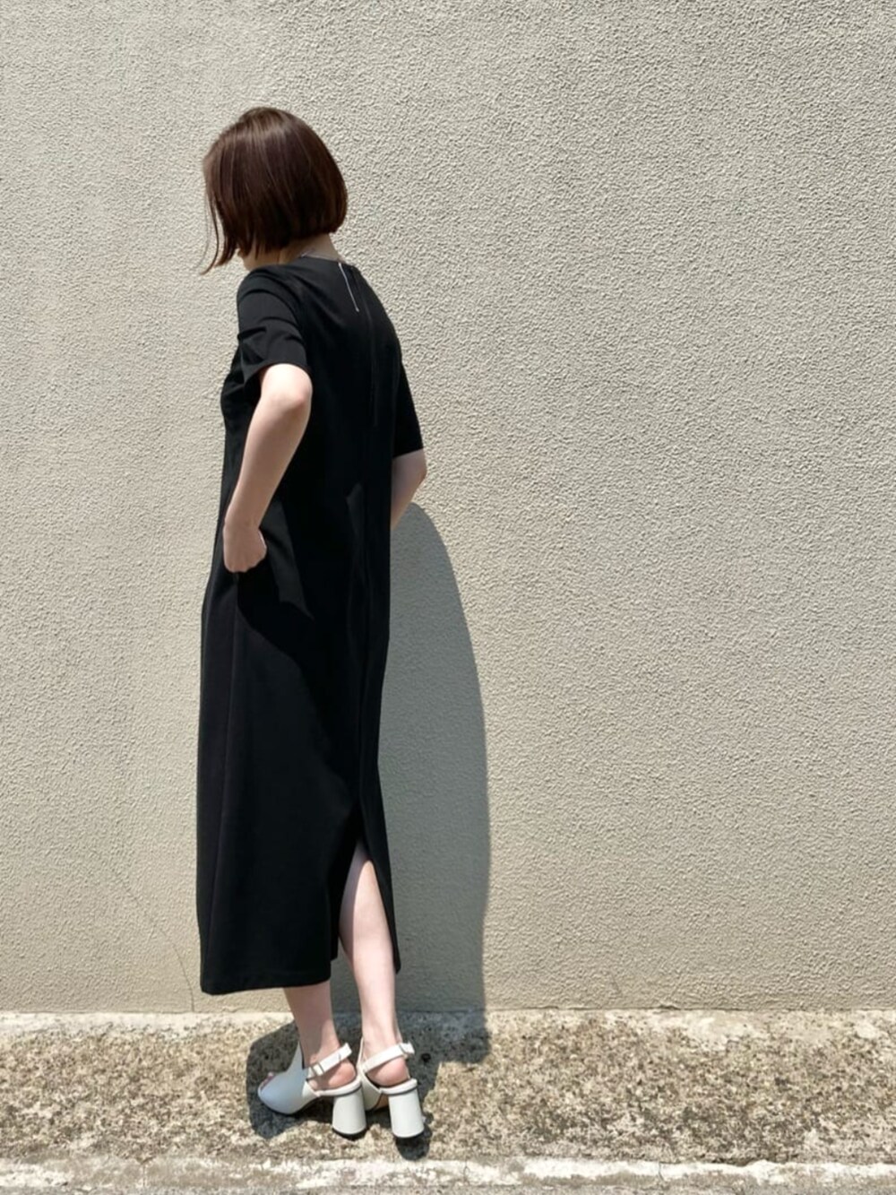 ホワイト系のサンダル、ブラック系のワンピース、シルバー系のネックレスを着用したレディースの春コーディネートの4枚目の写真