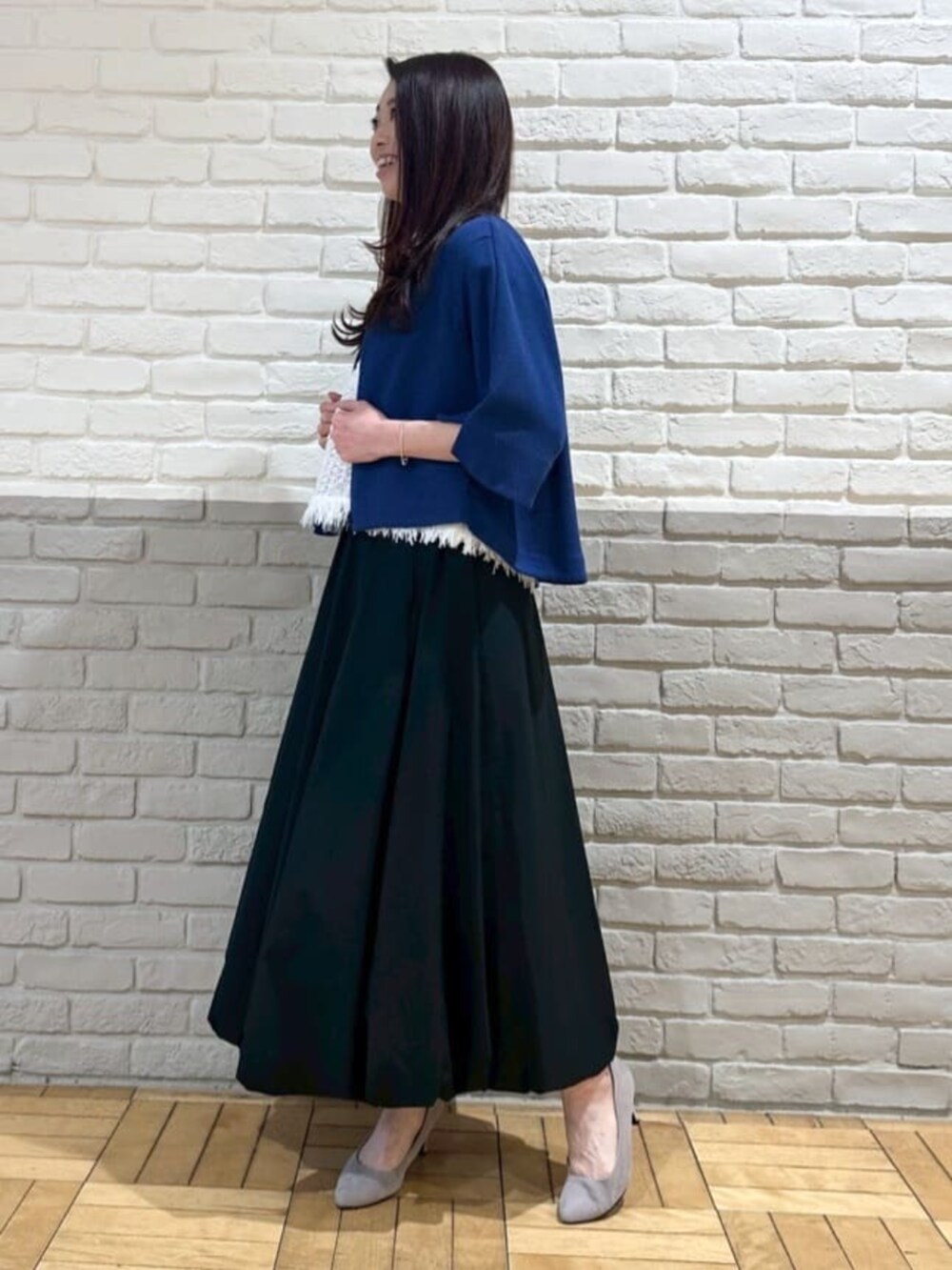 ホワイト系のニット/セーター、ブラック系のスカート、ブルー系のブルゾンを着用したレディースの夏コーディネートの2枚目の写真