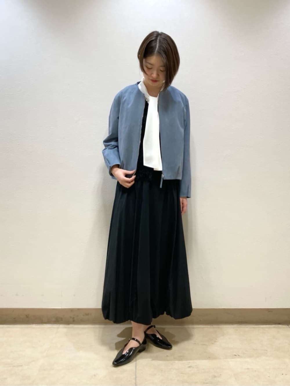 ブラック系のスカート、ブラック系のパンプス、ブルー系のブルゾンを着用したレディースの冬コーディネートの3枚目の写真