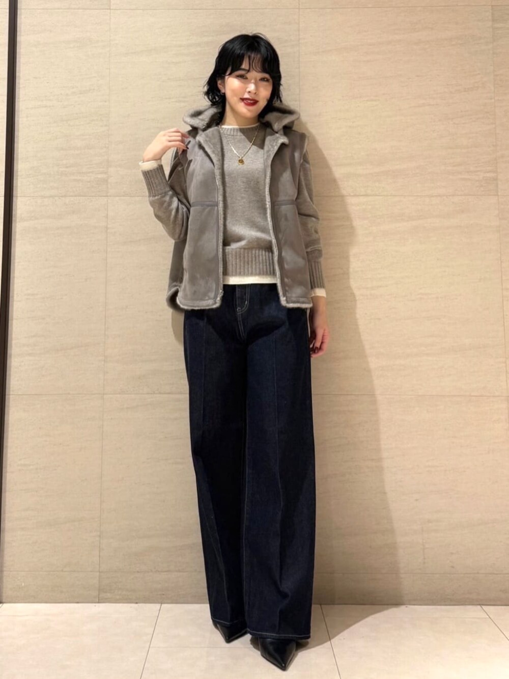 ブルー系のデニムパンツ、ベージュ系のベスト、ブラウン系のニット/セーターを着用したレディースの秋コーディネートの5枚目の写真