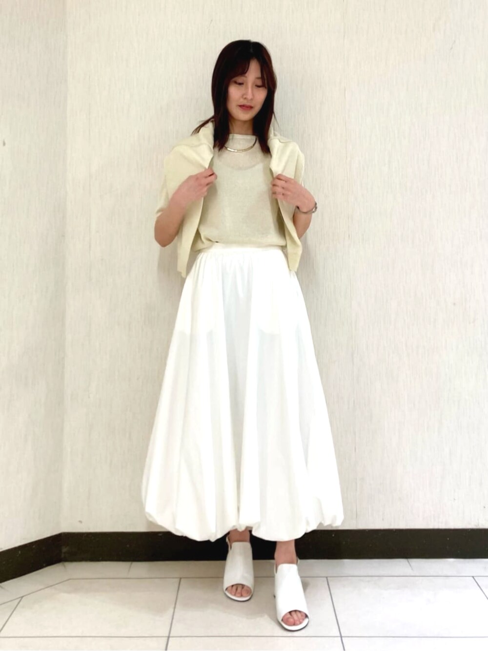 ホワイト系のスカート、イエロー系のカーディガン/ボレロ、イエロー系のニット/セーターを着用したレディースの春コーディネートの2枚目の写真