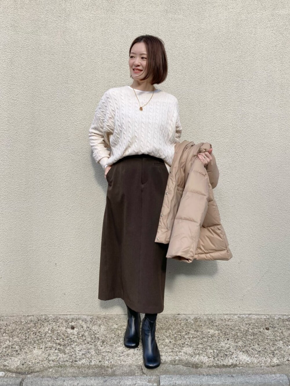 ブラック系のブーツ、ベージュ系のダウンジャケット/コート、ブラウン系のスカートを着用したレディースの冬コーディネートの5枚目の写真
