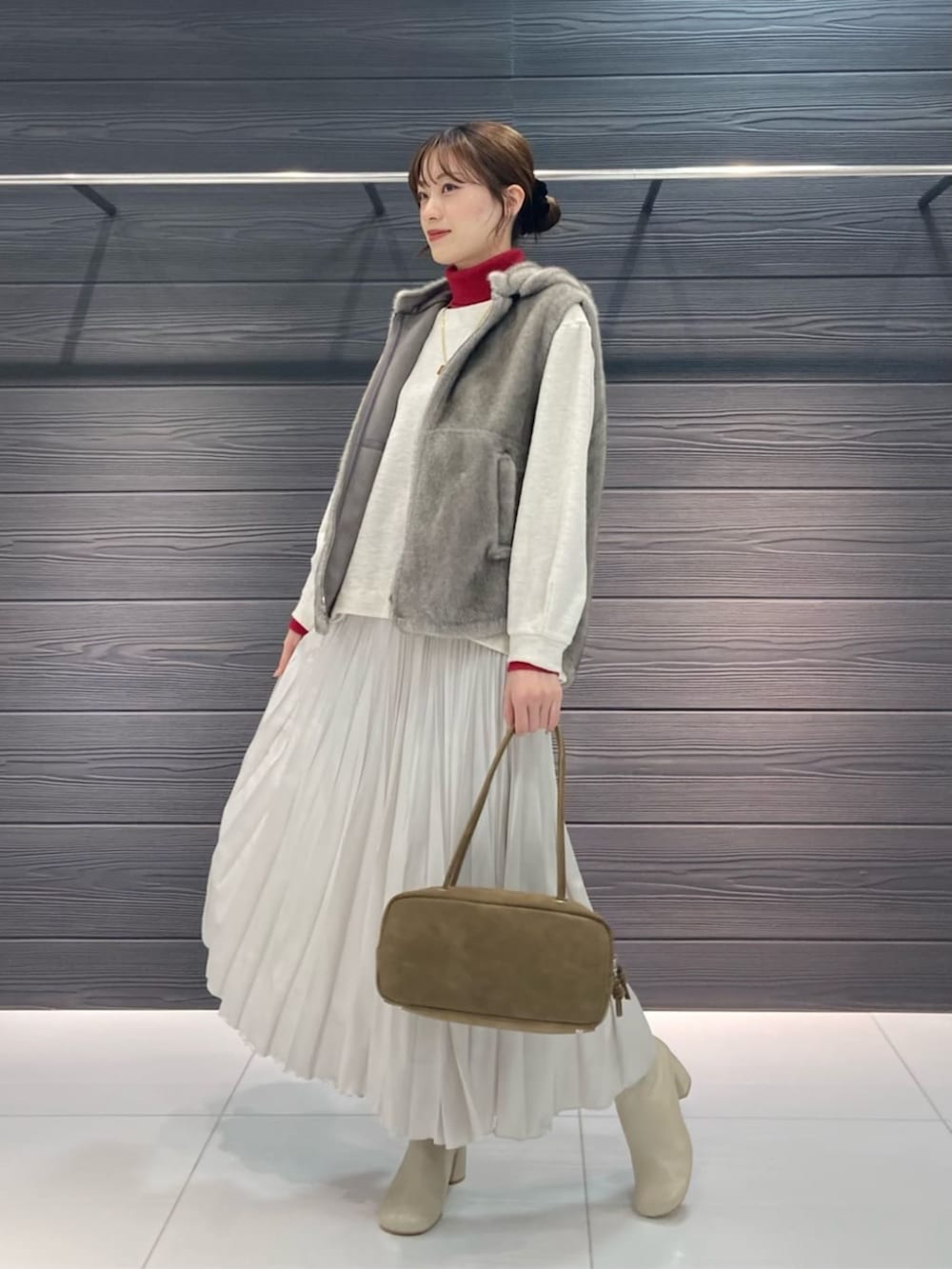 ベージュ系のベスト、ホワイト系のブーツ、ホワイト系のスカートを着用したレディースの秋コーディネートの4枚目の写真