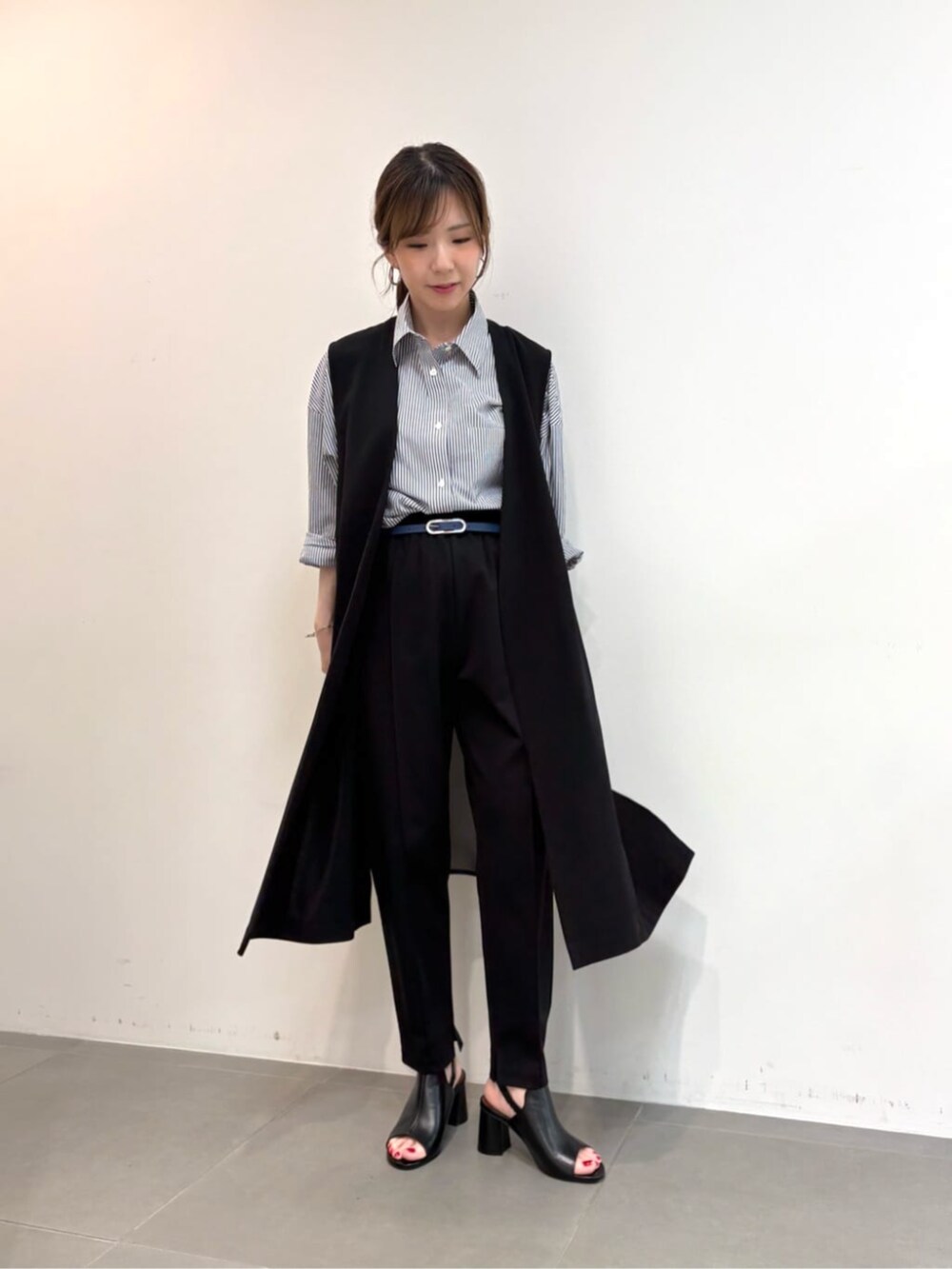 ブルー系のシャツ/ブラウス、ブラック系のサンダル、ブラック系のベストを着用したレディースの春コーディネートの2枚目の写真