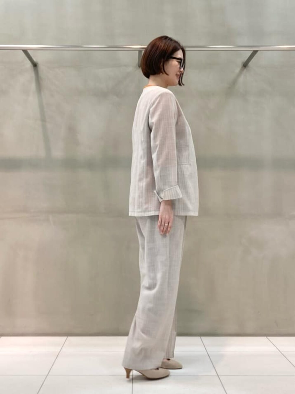 オレンジ系のニット/セーター、ホワイト系のノーカラージャケット、ホワイト系のスラックスを着用したレディースの春コーディネートの3枚目の写真