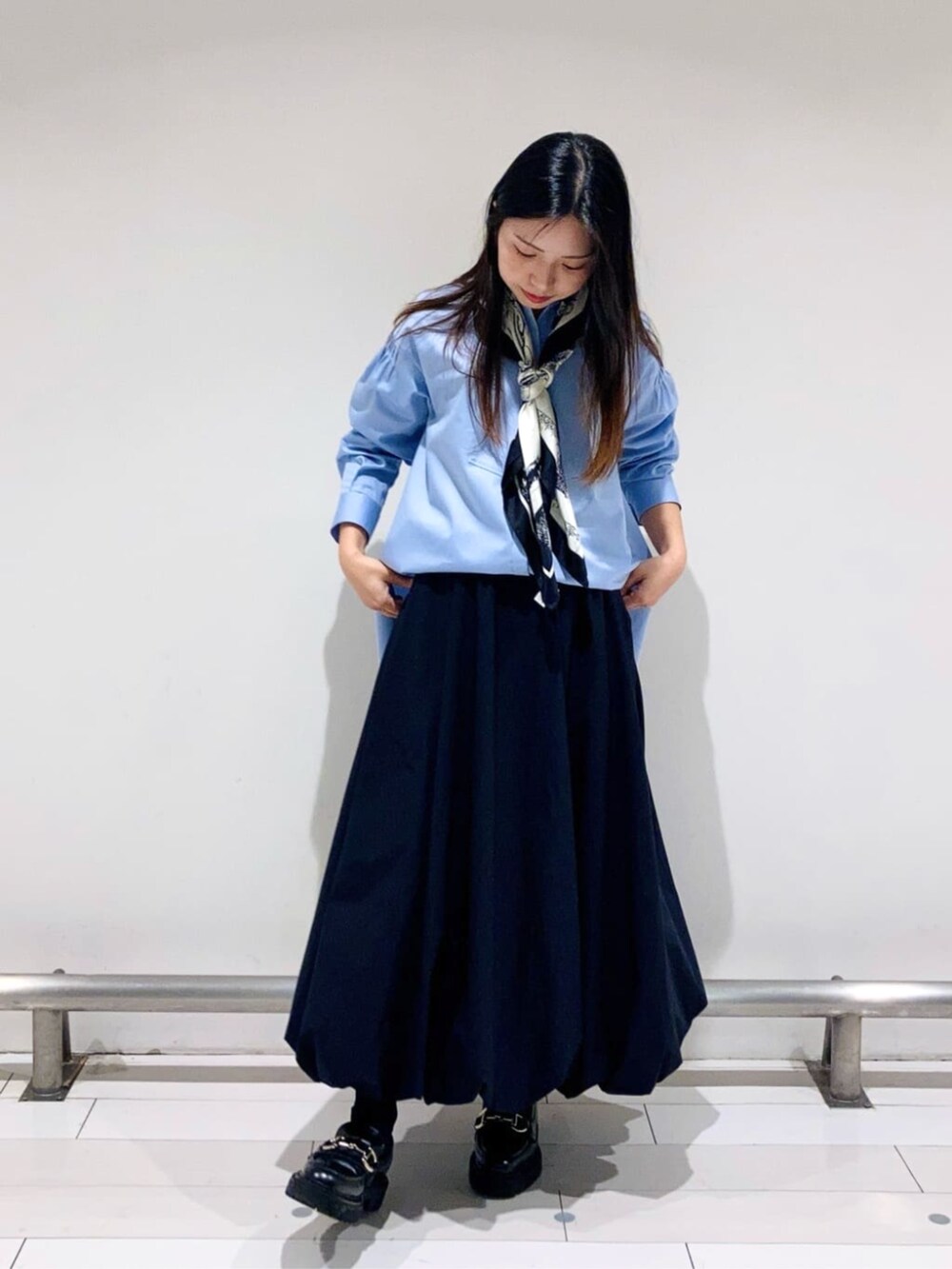 ブラック系のスカート、ブルー系のシャツ/ブラウス、ブラック系のストール/ショールを着用したレディースの春コーディネートの2枚目の写真
