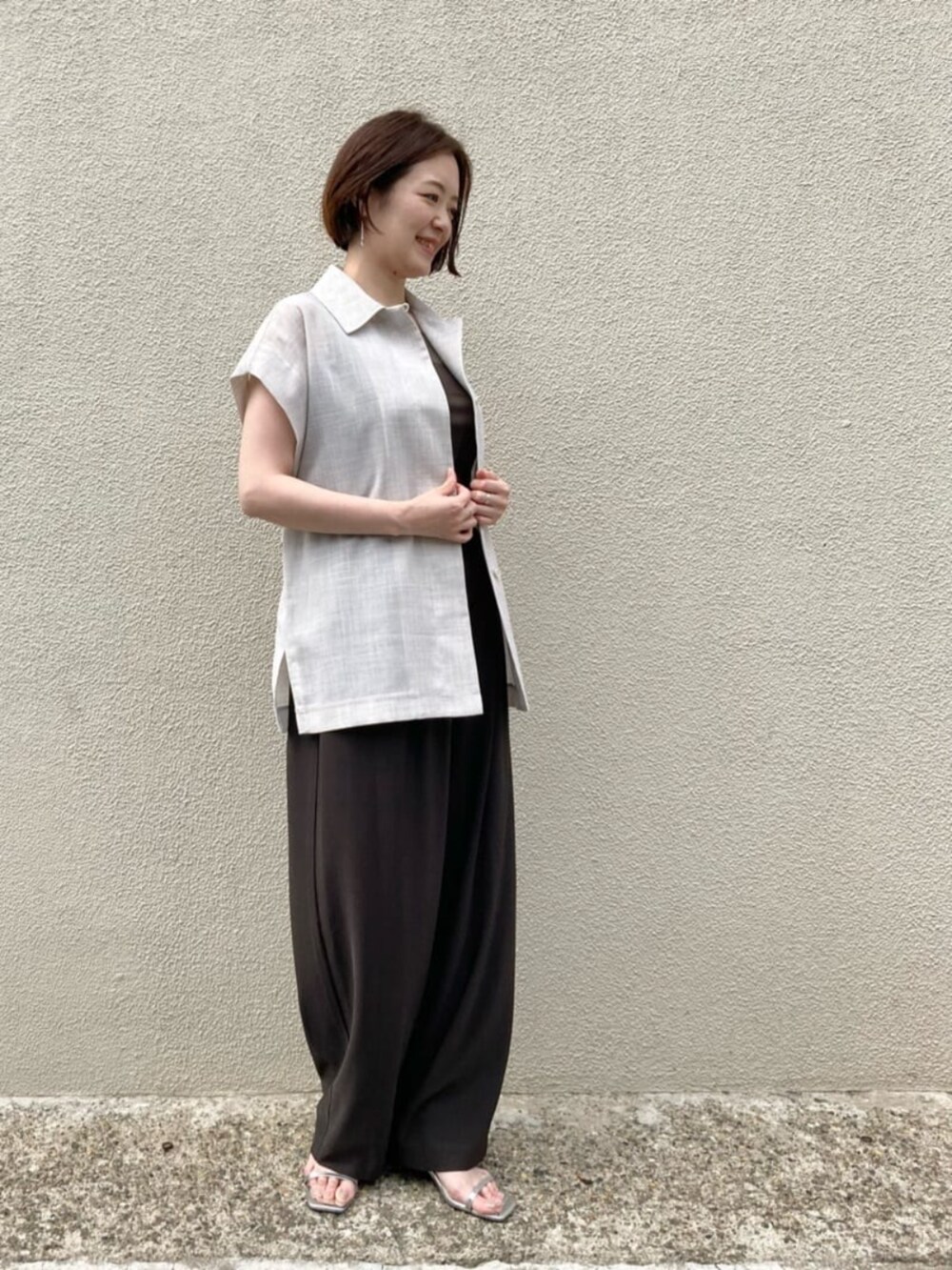 ブラウン系のキャミソール、ホワイト系のベスト、ブラウン系のパンツを着用したレディースの夏コーディネートの3枚目の写真