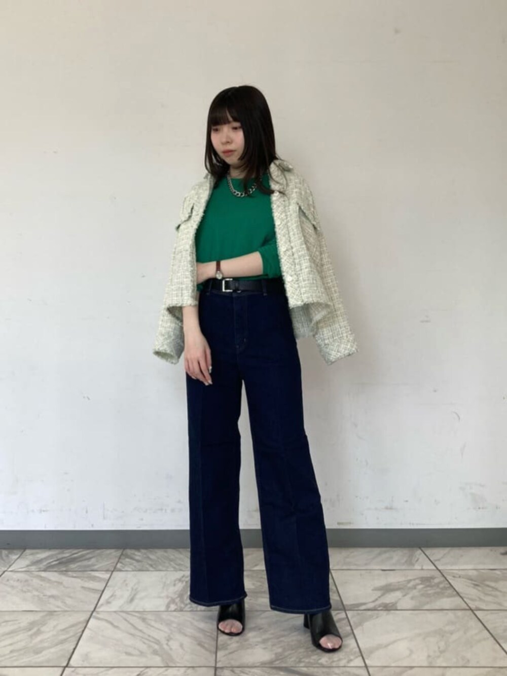 ブルー系のデニムパンツ、グリーン系のニット/セーター、ブラック系のサンダルを着用したレディースの春コーディネートの3枚目の写真