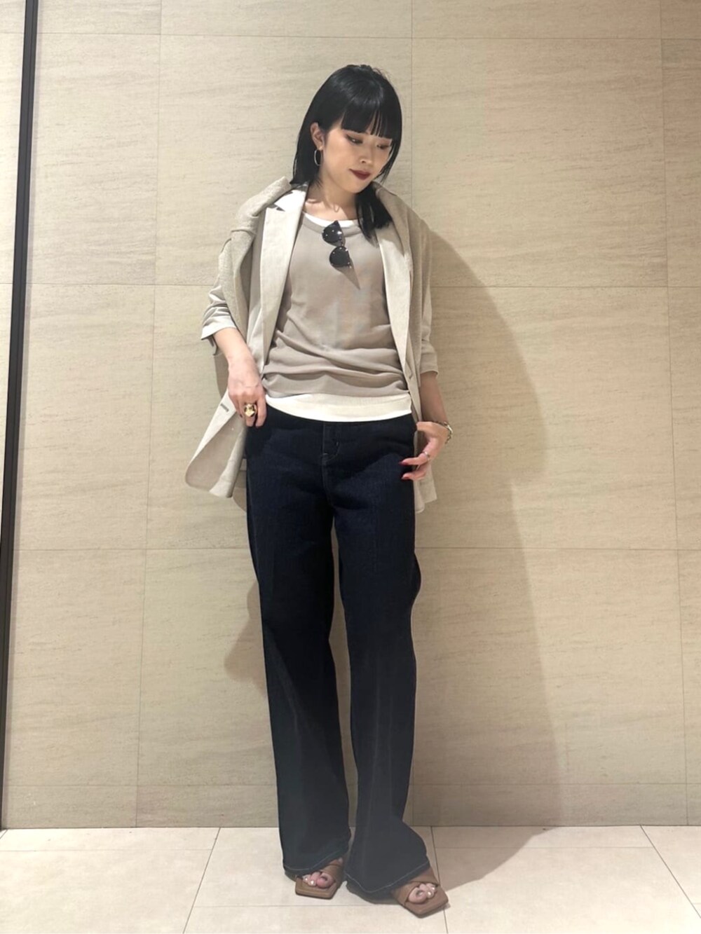 ブルー系のデニムパンツ、ベージュ系のテーラードジャケット、ベージュ系のタンクトップを着用したレディースの夏コーディネートの3枚目の写真