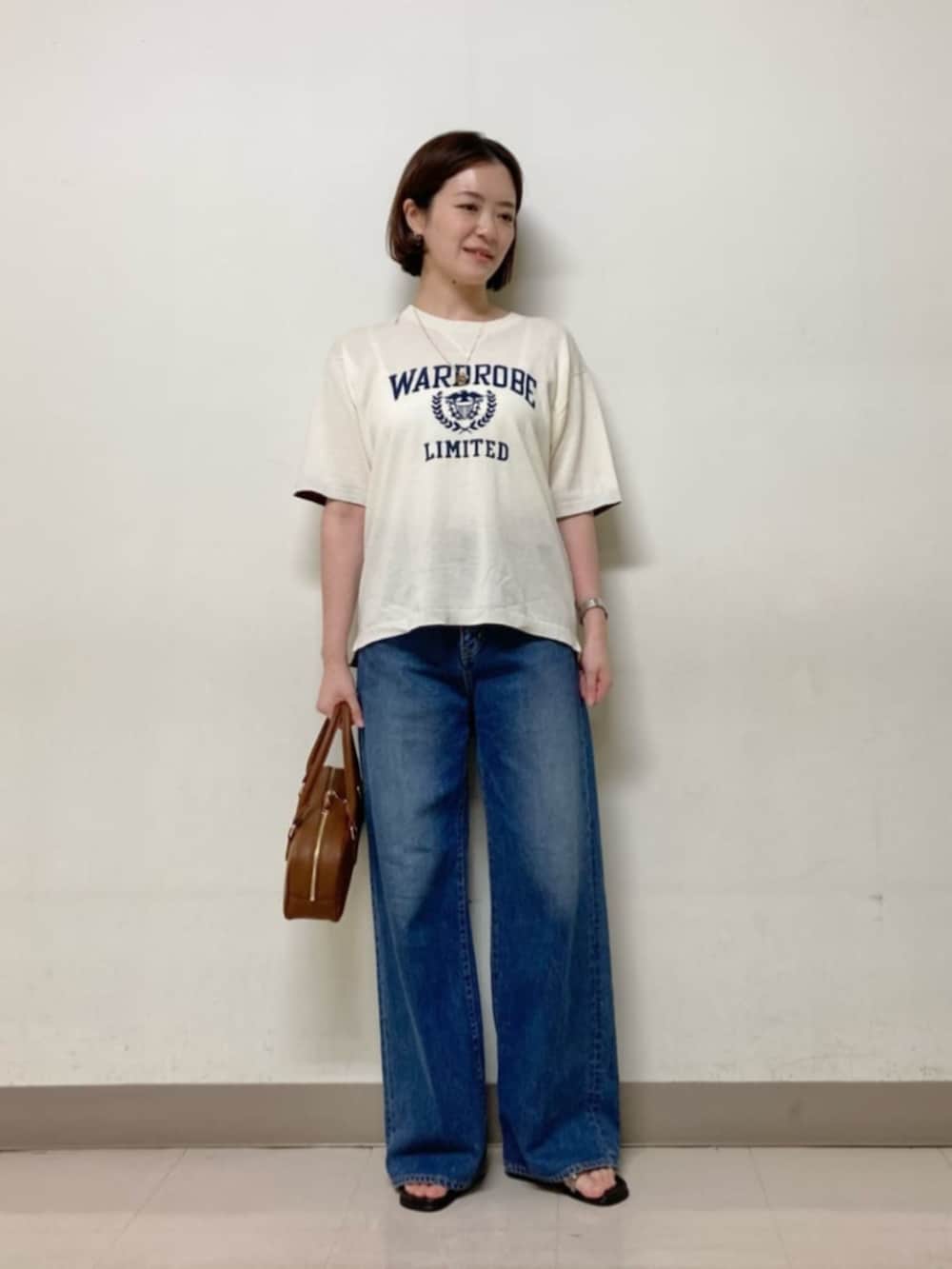 ブラウン系のボストンバッグ、ブルー系のデニムパンツ、ホワイト系のニット/セーターを着用したレディースの春コーディネートの6枚目の写真