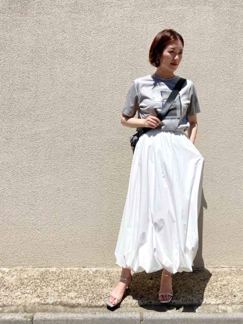 ホワイト系のスカート、ベージュ系のTシャツ/カットソーを着用したレディースの夏コーディネートの2枚目の写真