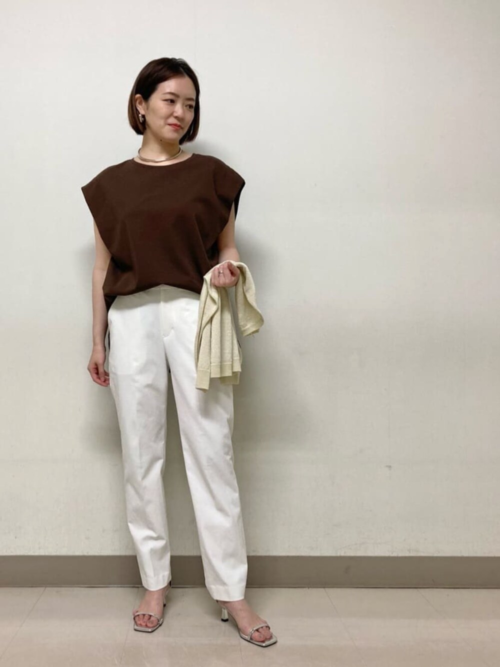 イエロー系のカーディガン/ボレロ、ブラウン系のTシャツ/カットソー、ホワイト系のパンツを着用したレディースの春コーディネートの2枚目の写真