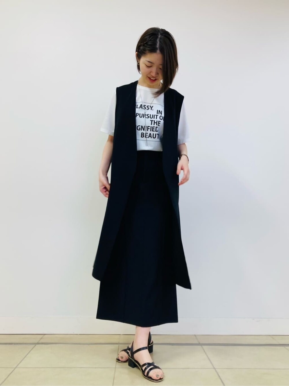 ホワイト系のTシャツ/カットソー、ブラック系のベスト、ブラック系のスカートを着用したレディースの夏コーディネートの2枚目の写真