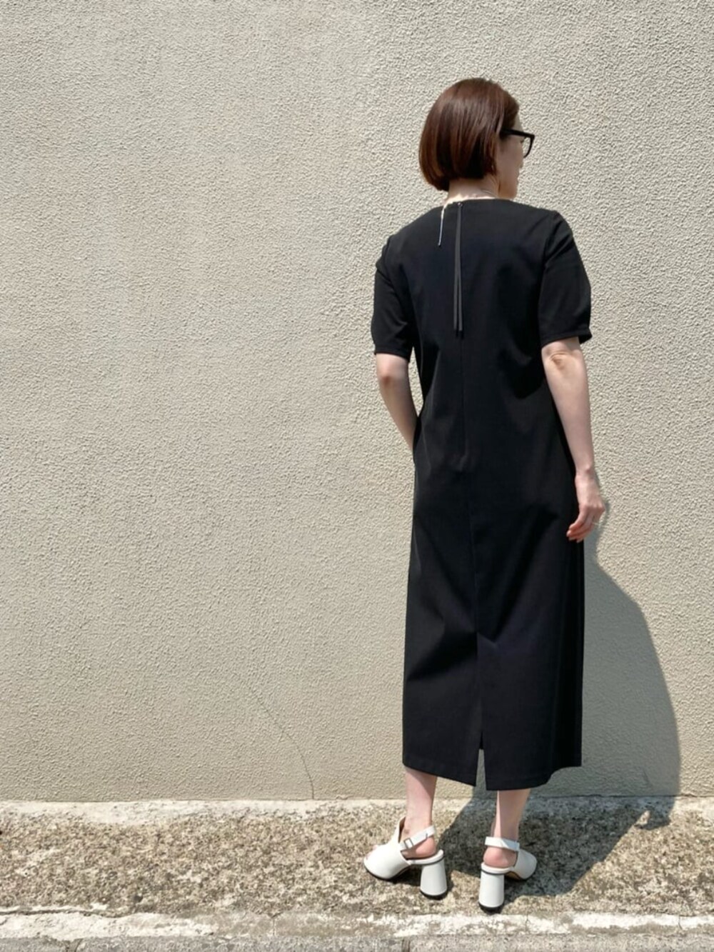 ホワイト系のサンダル、ブラック系のワンピース、シルバー系のネックレスを着用したレディースの春コーディネートの5枚目の写真