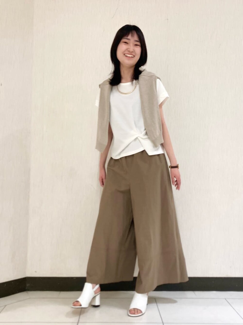 ベージュ系のカーディガン/ボレロ、ホワイト系のサンダル、ホワイト系のTシャツ/カットソーを着用したレディースの春コーディネートの3枚目の写真