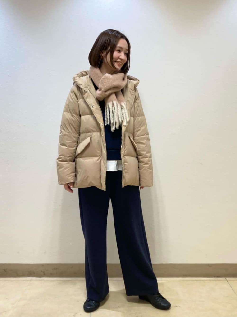 ベージュ系のダウンジャケット/コート、ブルー系のスラックスを着用したレディースの冬コーディネートの2枚目の写真