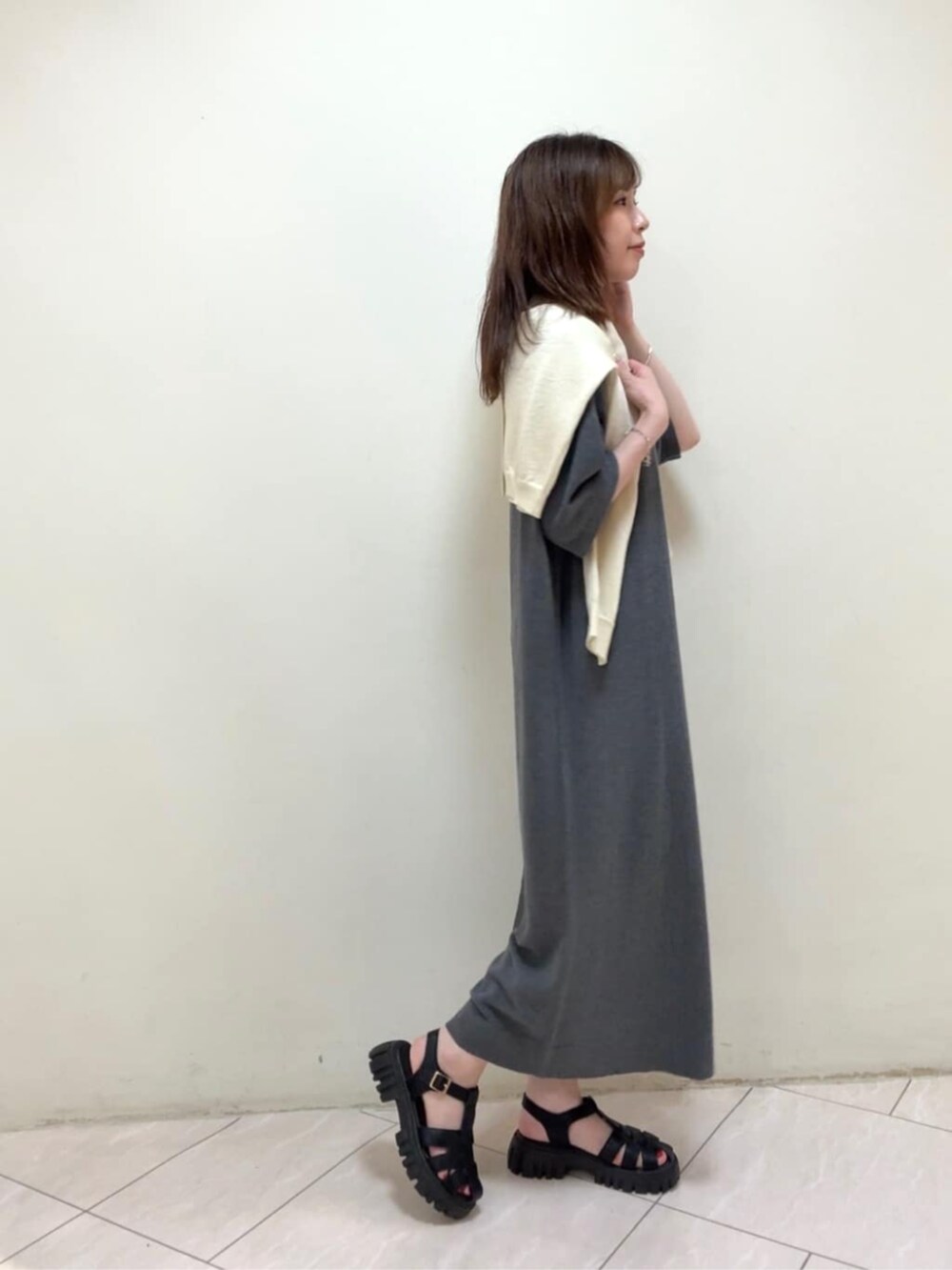 イエロー系のカーディガン/ボレロ、グレー系のワンピース、ホワイト系のネックレスを着用したレディースの春コーディネートの4枚目の写真