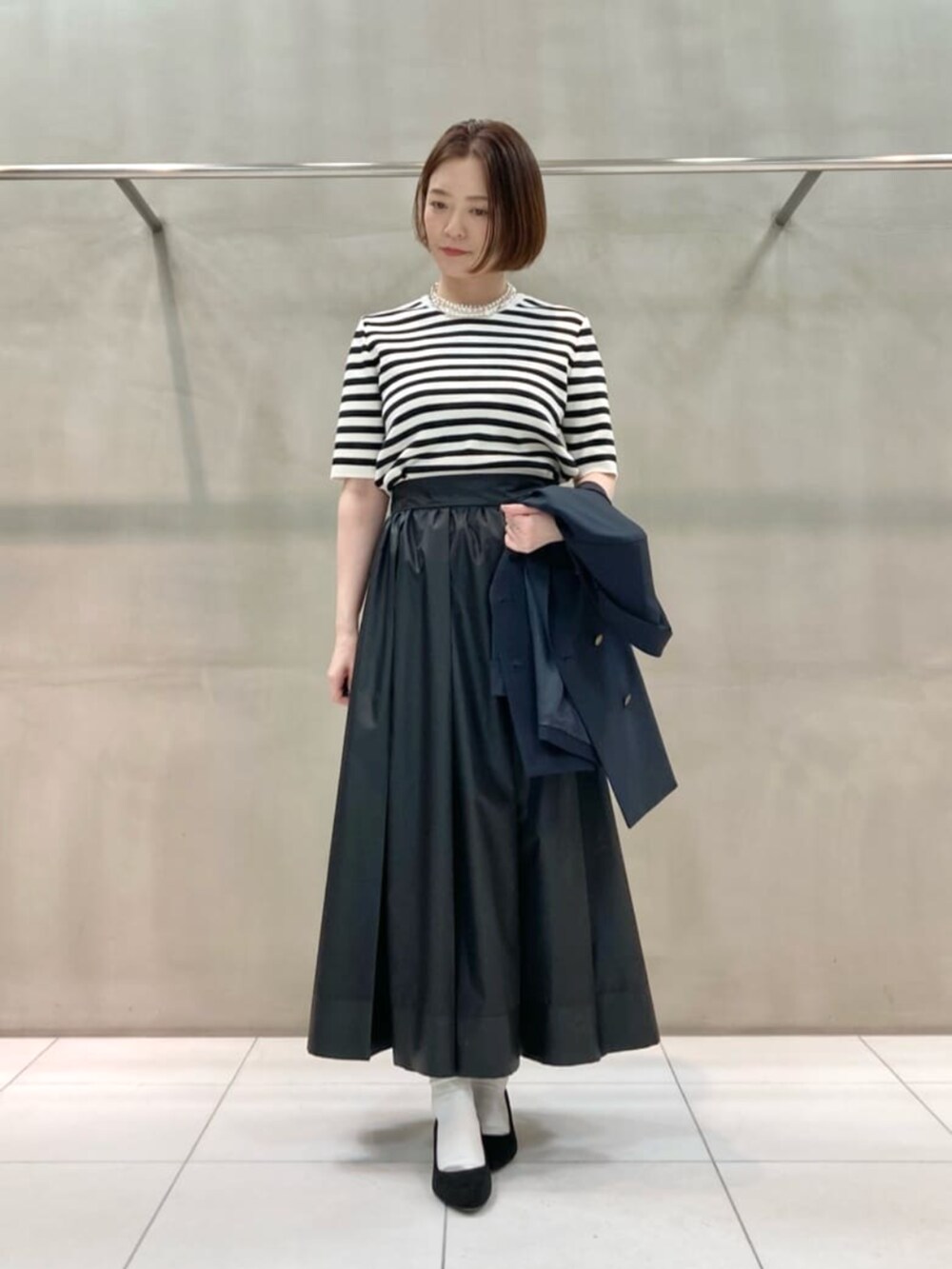 ブルー系のセットアップ、ホワイト系のニット/セーター、ブラック系のスカートを着用したレディースの春コーディネートの3枚目の写真