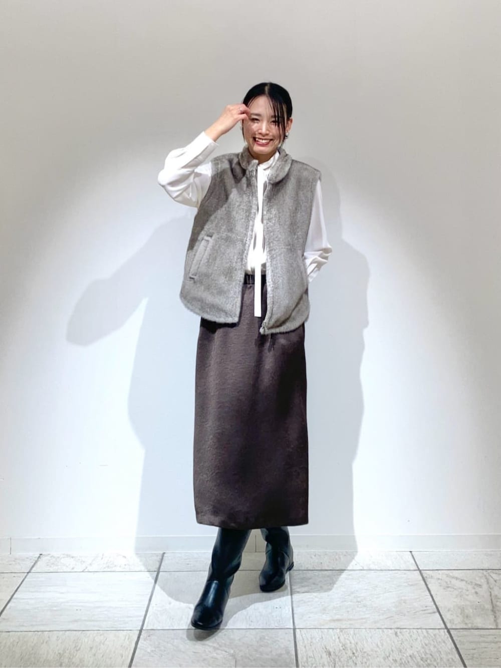 ベージュ系のベスト、ブラック系のスカート、ホワイト系のシャツ/ブラウスを着用したレディースの冬コーディネートの3枚目の写真