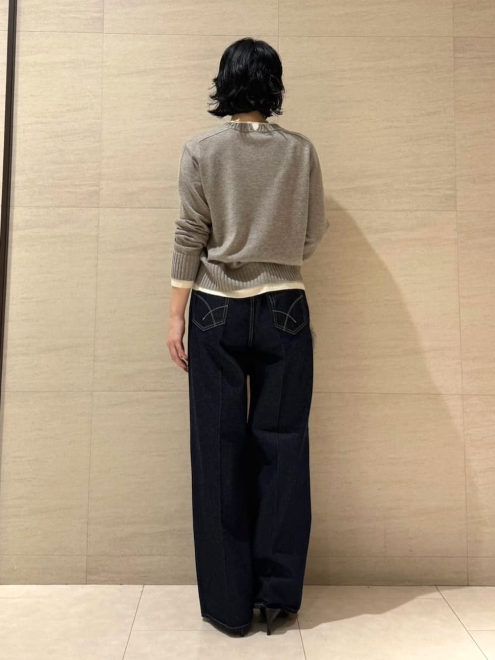 ブルー系のデニムパンツ、ベージュ系のベスト、ブラウン系のニット/セーターを着用したレディースの秋コーディネートの9枚目の写真