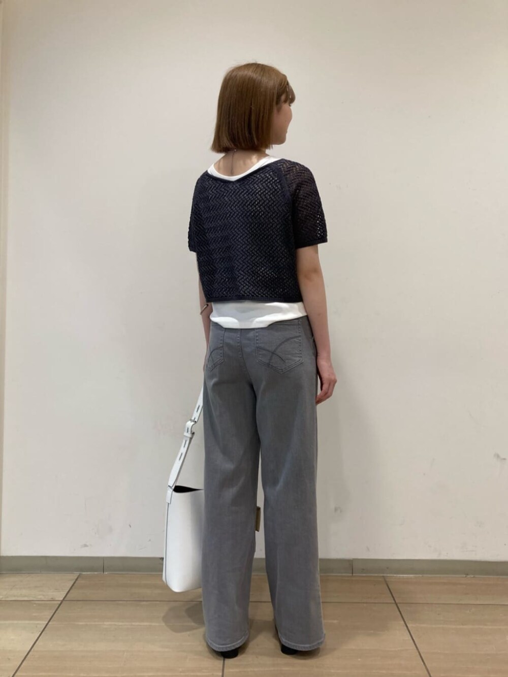 ホワイト系のショルダーバッグ、グレー系のデニムパンツ、グレー系のアンサンブルを着用したレディースの秋コーディネートの5枚目の写真