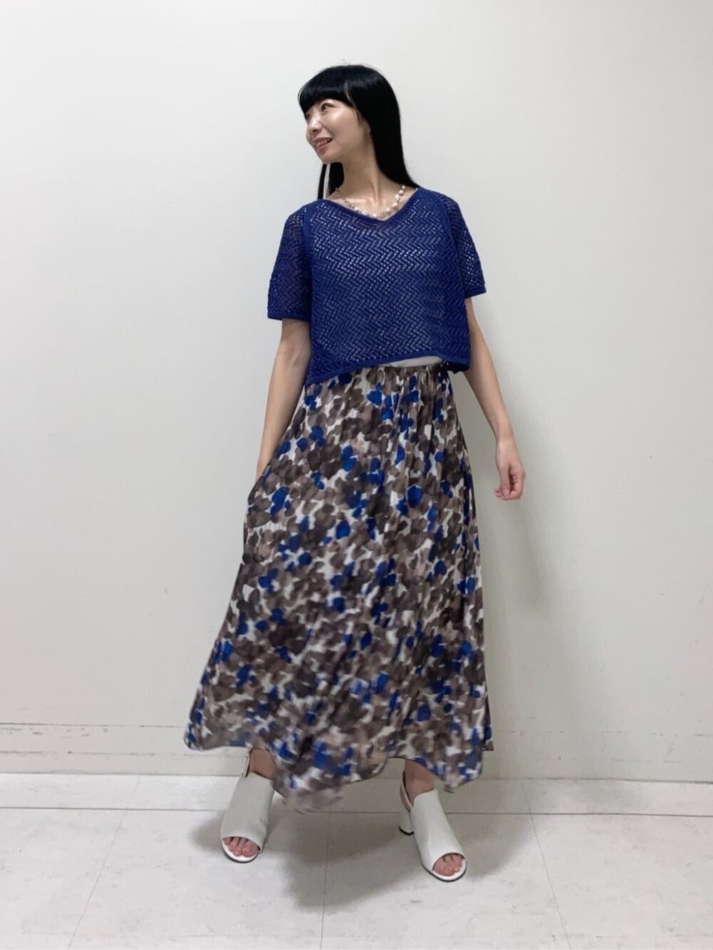 ホワイト系のサンダル、ブラウン系のスカート、ブルー系のアンサンブルを着用したレディースの夏コーディネートの2枚目の写真