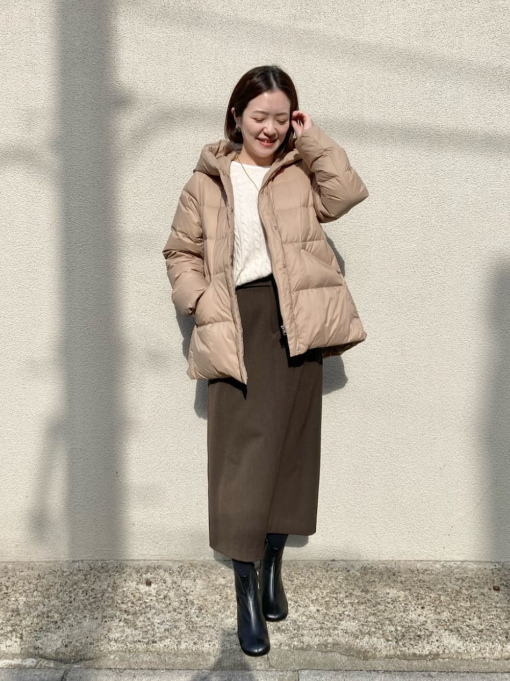 ブラック系のブーツ、ベージュ系のダウンジャケット/コート、ブラウン系のスカートを着用したレディースの冬コーディネートの2枚目の写真
