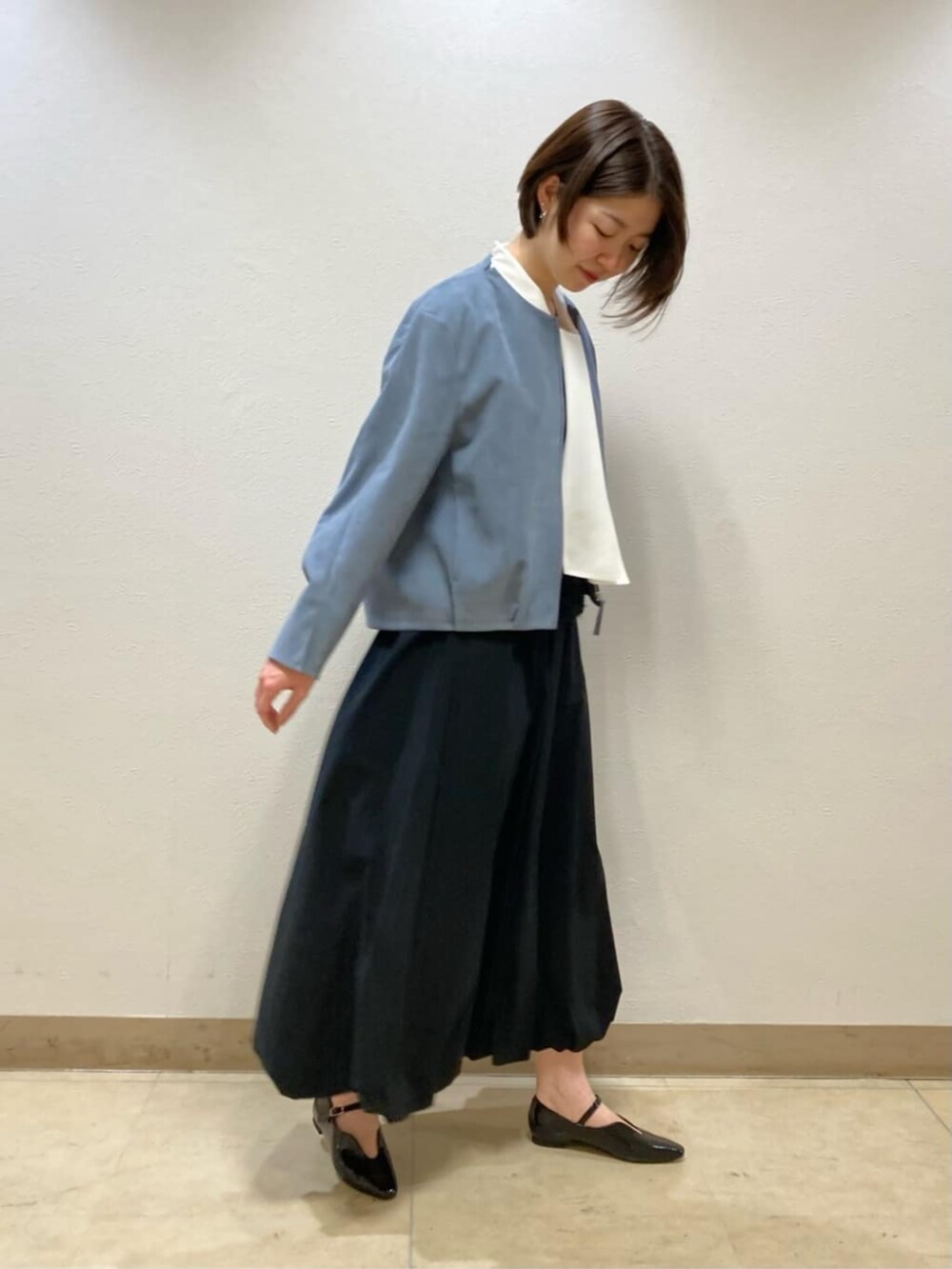 ブラック系のスカート、ブラック系のパンプス、ブルー系のブルゾンを着用したレディースの冬コーディネートの2枚目の写真