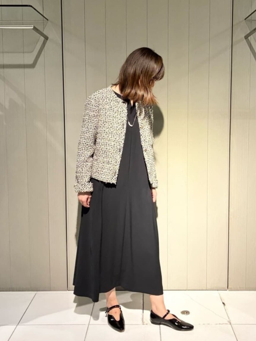 ベージュ系のノーカラージャケット、ブラック系のワンピース、ブラック系のパンプスを着用したレディースの冬コーディネートの2枚目の写真