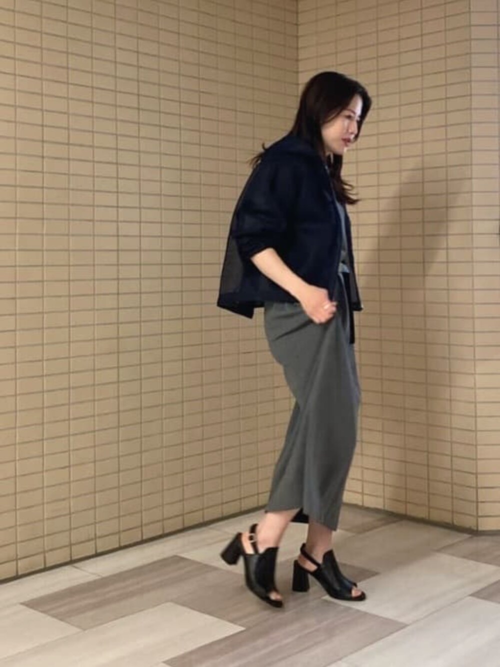 ブラック系のサンダル、グレー系のワンピース、ブルー系のブルゾンを着用したレディースの夏コーディネートの2枚目の写真