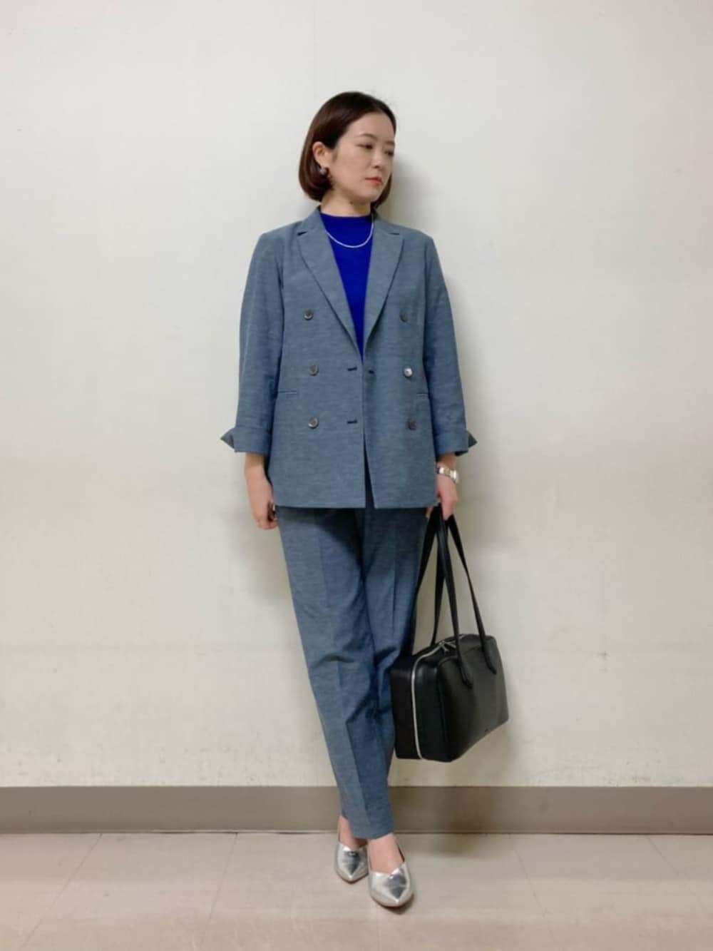 ブルー系のテーラードジャケット、ブルー系のその他パンツ、ブラック系のボストンバッグを着用したレディースの春コーディネートの2枚目の写真