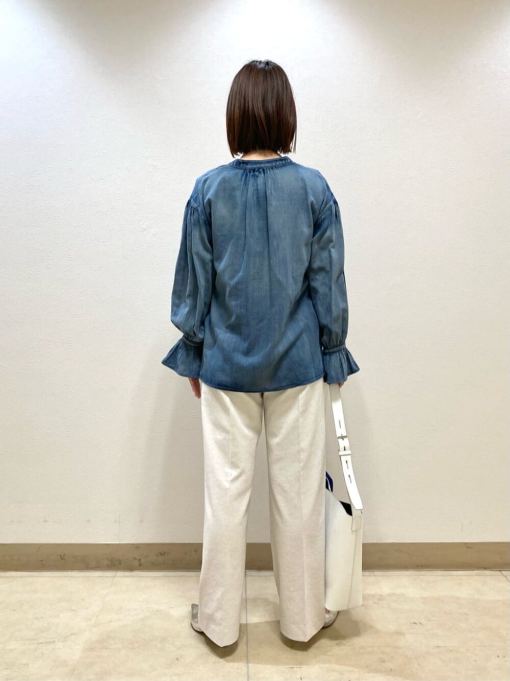 ホワイト系のショルダーバッグ、シルバー系のパンプス、ホワイト系のスラックスを着用したレディースの春コーディネートの5枚目の写真
