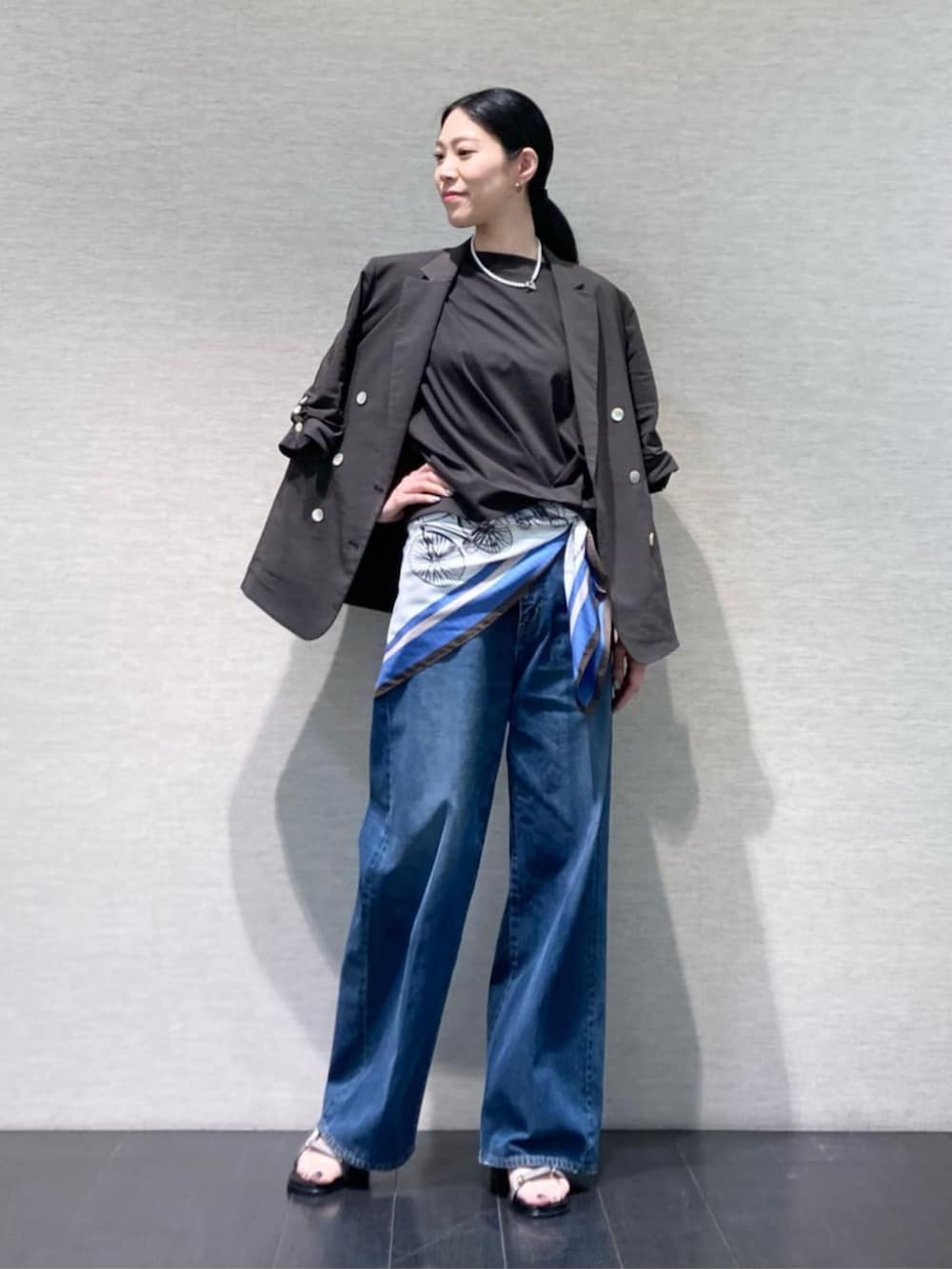 ブルー系のデニムパンツ、グレー系のテーラードジャケット、グレー系のサンダルを着用したレディースの夏コーディネートの2枚目の写真