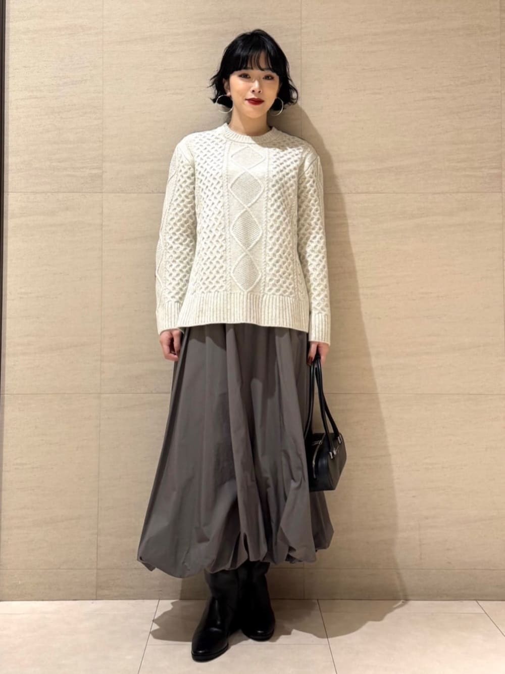 グレー系のチェスターコート、グリーン系のスカートを着用したレディースの冬コーディネートの3枚目の写真