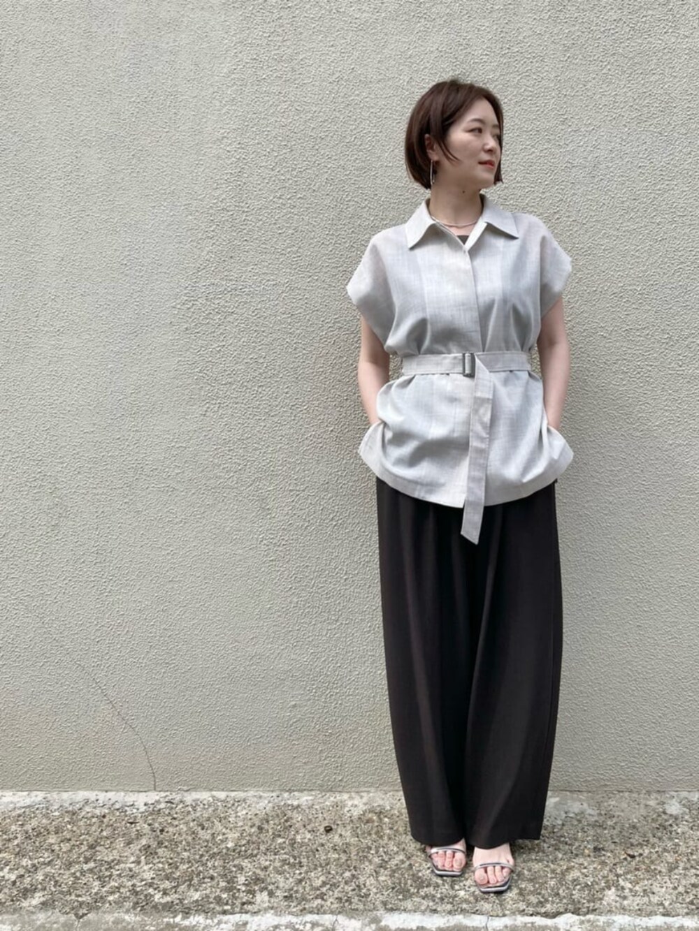 ブラウン系のキャミソール、ホワイト系のベスト、ブラウン系のパンツを着用したレディースの夏コーディネートの4枚目の写真