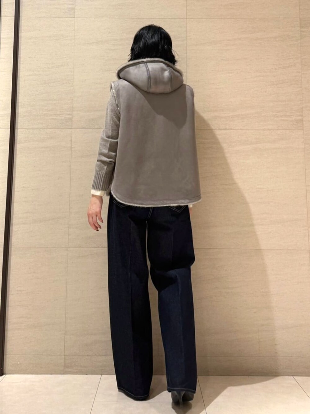 ブルー系のデニムパンツ、ベージュ系のベスト、ブラウン系のニット/セーターを着用したレディースの秋コーディネートの6枚目の写真