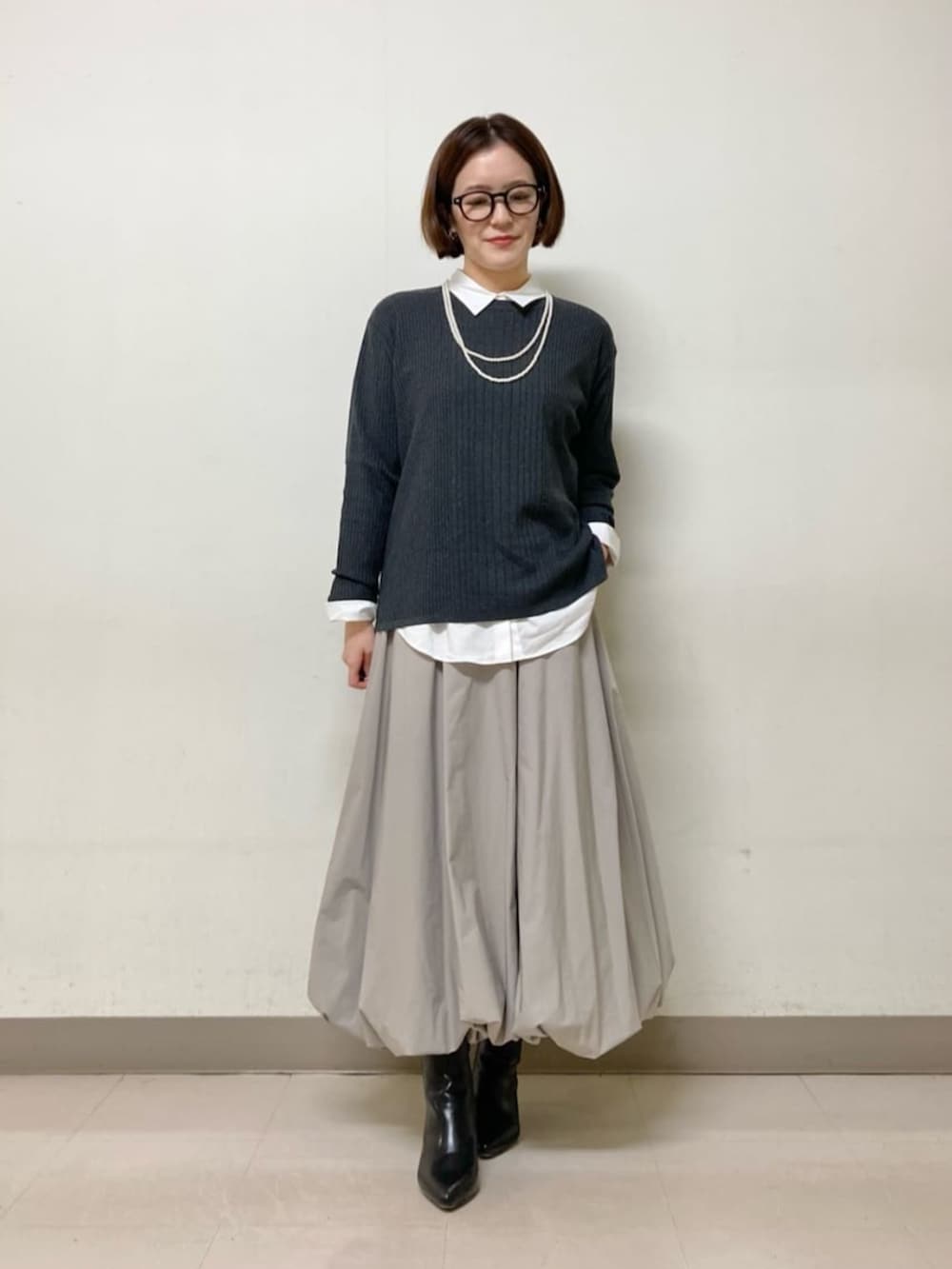 ベージュ系のスカート、グレー系のニット/セーター、ホワイト系のシャツ/ブラウスを着用したレディースの冬コーディネートの2枚目の写真