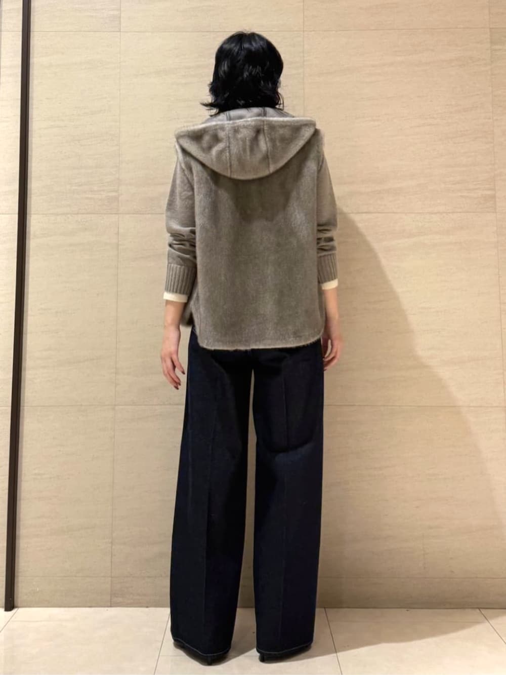 ブルー系のデニムパンツ、ベージュ系のベスト、ブラウン系のニット/セーターを着用したレディースの秋コーディネートの3枚目の写真